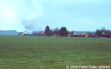 Zum Vergrößern klicken - Die 52 7596 entschwindet mit ihren historischen Wagen Richtung Roßberg (Mennisweiler, 6. April 2003).