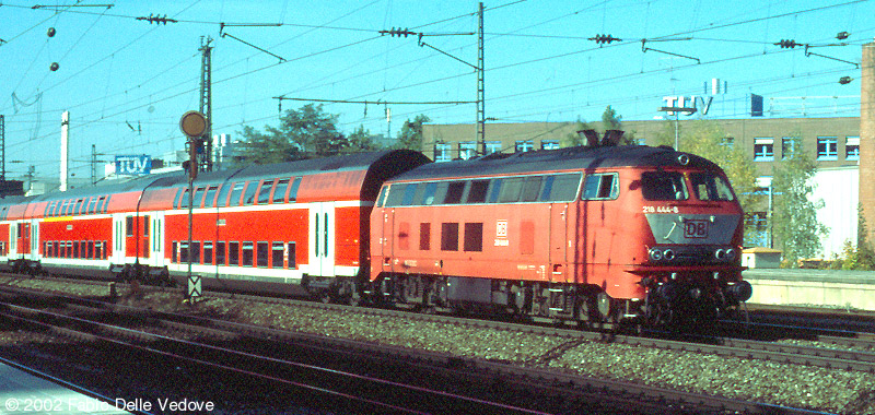 Die orientrote 218 444-8 vor einem verkehrsroten Dosto-Zug nach Mühldorf (München Heimeranplatz, Oktober 2001)