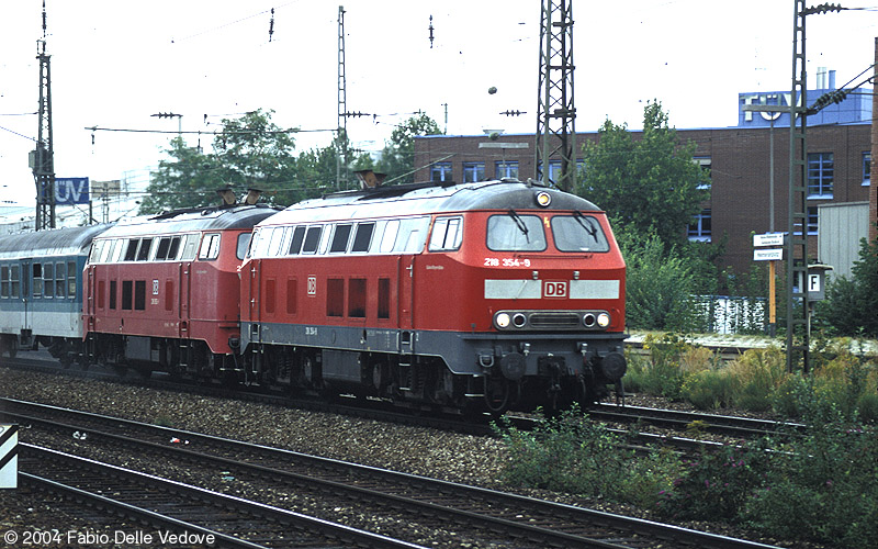 Die verkehrsrote 218 354-9 und eine orientrote 218 vor RB 31463 (München Hbf 15:14 - München Ost 15:22 - Mühldorf (Obb) - 16:19/16:28 - Simbach (Inn) 16:59) um 15:17 Uhr (München Heimeranplatz, September 2003).
