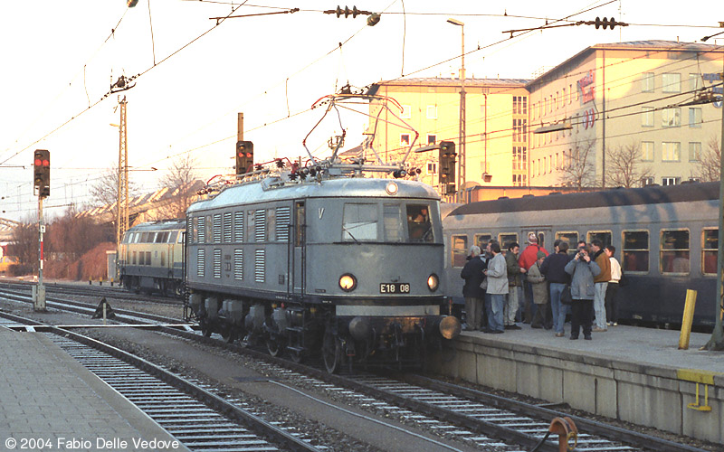 Die Altbauellok wird schon sehnsüchtig von den Eisenbahnenthusiasten erwartet. Der abfahrende Nahverkehrszug im Hintergrund mit seiner oceanblau-beigen 218 und den Silberlingen ist auch schon lange Geschichte (München Hauptbahnhof, 1990).